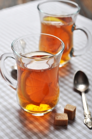 Tea with lemon in glass cups on checkered napkinの写真素材