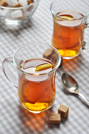 Tea with lemon in glass cups on checkered napkinの写真素材