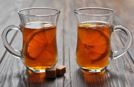 Tea with lemon in glass cups on wooden backgroundの写真素材