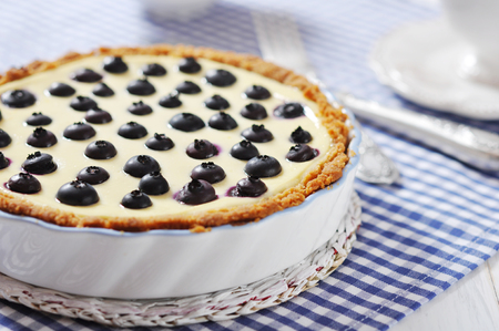 Blueberry tart with cup of tea on checkered backgroundの写真素材