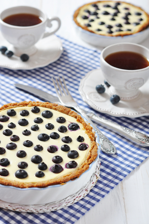 Blueberry tart with cup of tea on checkered backgroundの写真素材