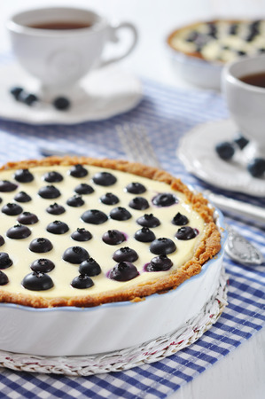 Blueberry tart with cup of tea on checkered backgroundの写真素材