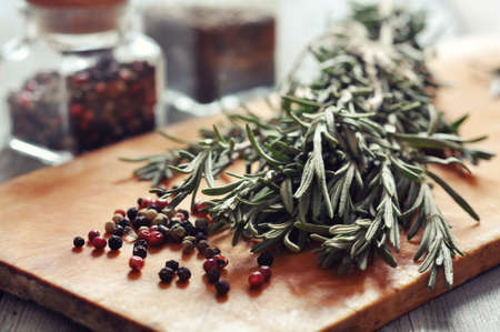 Fresh rosemary and pepper on a wooden board closeupの写真素材
