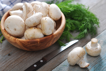 Fresh mushrooms champignon in bowl on wooden backgroundの写真素材