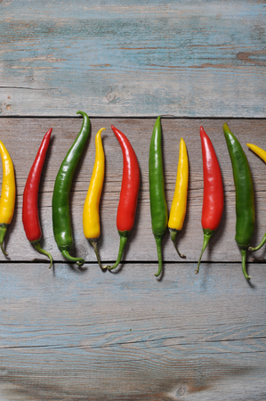 Multi colored hot chili peppers in row on vintage wooden backgroundの写真素材