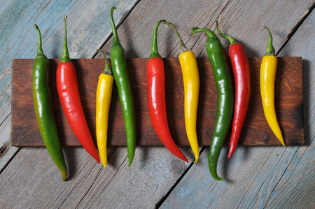 Multi colored hot chili peppers in row on vintage wooden backgroundの写真素材