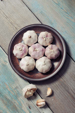 Fresh garlic on brown plate on vintage wooden backgroundの写真素材