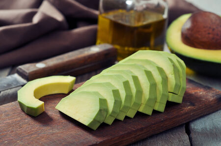 Fresh sliced avocado on cutting board over wooden backgroundの写真素材