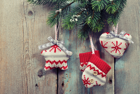 Christmas knitted decoration on fir tree branches on wooden backgroundの写真素材