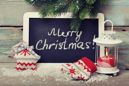 Christmas knitted decoration with candle in lantern and framed blackboard on wooden backgroundの写真素材