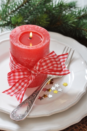 Christmas table setting with red candle and fir tree branchの写真素材
