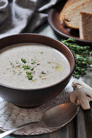 Mushroom cream soup with herbs in brown bowl over wooden backgroundの写真素材