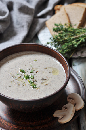 Mushroom cream soup with herbs in brown bowl over wooden backgroundの写真素材