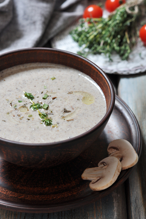 Mushroom cream soup with herbs in brown bowl over wooden backgroundの写真素材