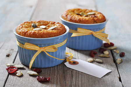 Pumpkin muffins in ceramic baking mold with yellow ribbon over wooden backgroundの写真素材