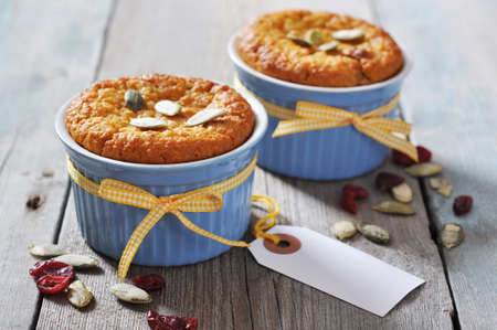 Pumpkin muffins in ceramic  baking mold with yellow ribbon over wooden backgroundの写真素材