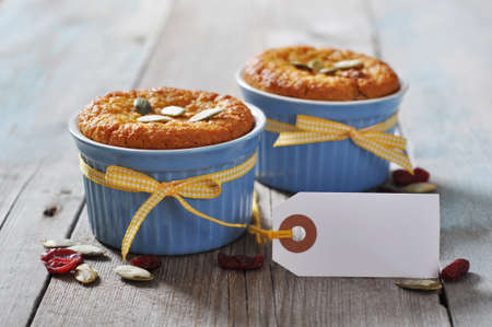 Pumpkin muffins in ceramic  baking mold with yellow ribbon over wooden backgroundの写真素材