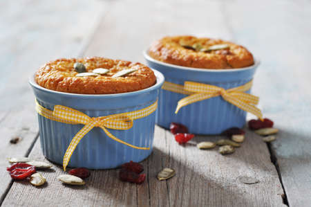 Pumpkin muffins in ceramic  baking mold with yellow ribbon over wooden backgroundの写真素材