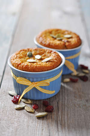 Pumpkin muffins in ceramic  baking mold with yellow ribbon over wooden backgroundの写真素材