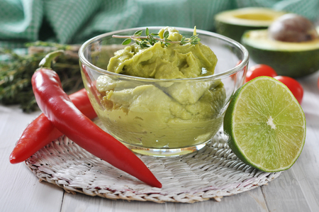 Sauce guacamole in a glass bowl over wooden backgroundの写真素材