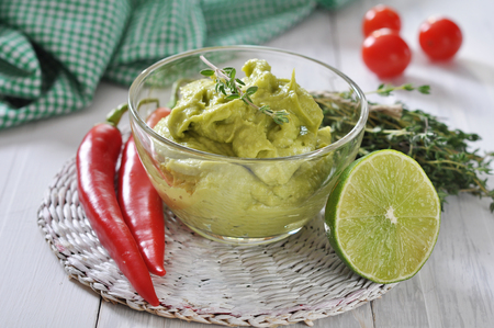Sauce guacamole in a glass bowl over wooden backgroundの写真素材