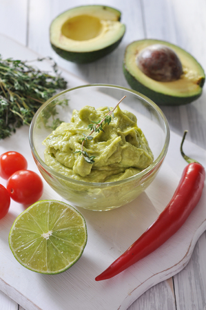 Sauce guacamole in a glass bowl over wooden backgroundの写真素材