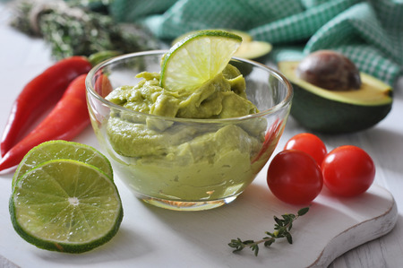 Sauce guacamole in a glass bowl over wooden backgroundの写真素材