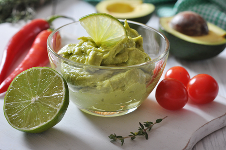 Sauce guacamole in a glass bowl over wooden backgroundの写真素材