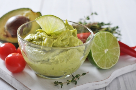 Sauce guacamole in a glass bowl over wooden backgroundの写真素材