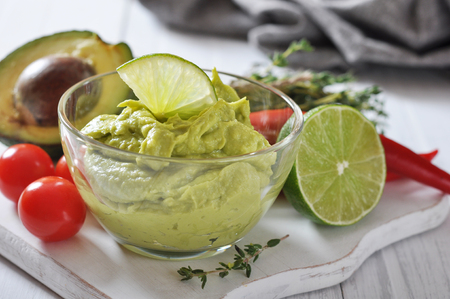 Sauce guacamole in a glass bowl over wooden backgroundの写真素材