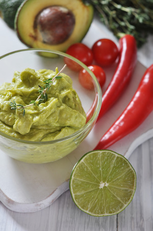 Sauce guacamole in a glass bowl over wooden backgroundの写真素材