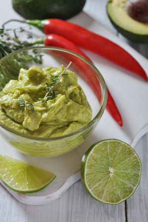 Sauce guacamole in a glass bowl over wooden backgroundの写真素材
