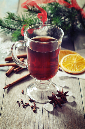 Mulled wine with spices and christmas decoration on wooden backgroundの写真素材