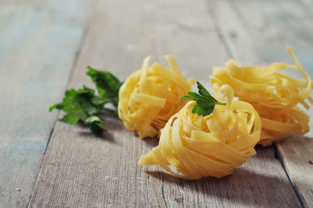 Homemade pasta fettuccine on wooden backgroundの写真素材