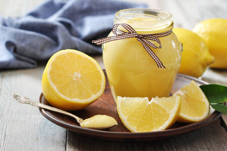 Lemon curd in glass jar with fresh lemons on wooden backgroundの写真素材