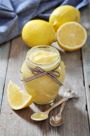 Lemon curd in glass jar with fresh lemons on wooden backgroundの写真素材
