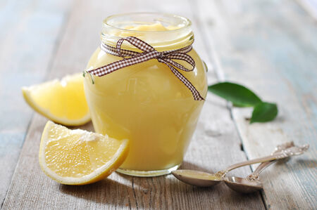 Lemon curd in glass jar with fresh lemons on wooden backgroundの写真素材