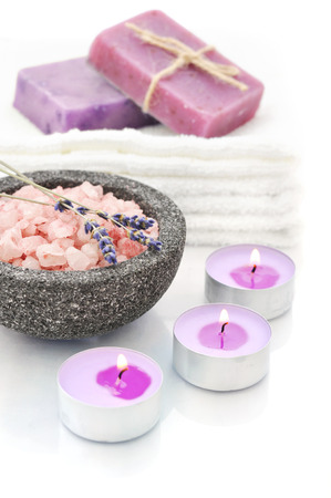 Sea salt in stone bowl with candles and herbal soap on a white background with reflectionの写真素材