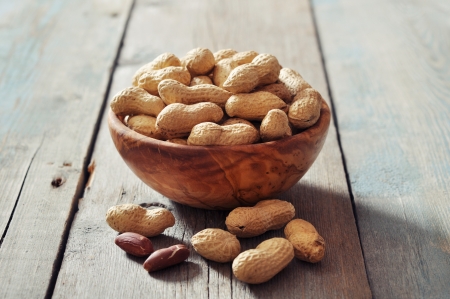 Unpeeled  peanuts in bowl on wooden background closeupの写真素材