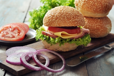 Sandwich with ham, cheese,  tomato and lettuce on wooden cutting board closeupの写真素材
