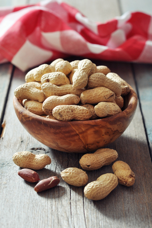 Unpeeled  peanuts in bowl on wooden background closeupの写真素材