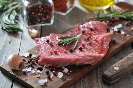 Raw beef steak with spices and rosemary on wooden backgroundの写真素材