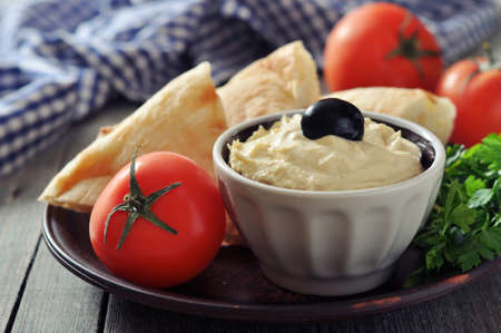 Bowl of fresh hummus  with olive and bread slices on wooden の写真素材