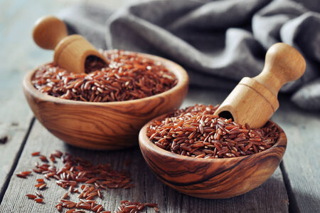 Red rice in a bowl with scoop on wooden の写真素材