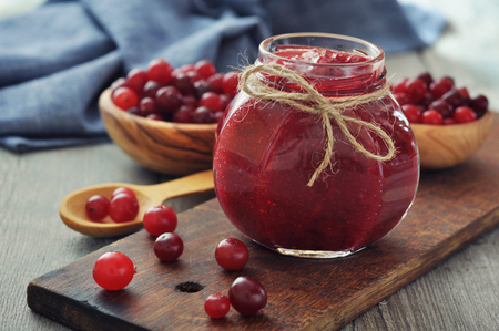 Cranberry jam in glass jar with fresh berry on wooden backgroundの写真素材