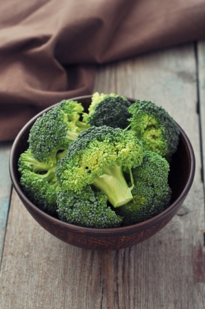 Bunch of fresh green broccoli on brown plate over wooden backgroundの写真素材