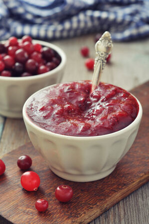 Cranberry sauce in ceramic bowl with fresh berry on wooden backgroundの写真素材