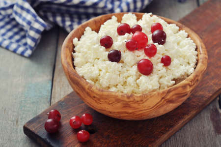Cottage cheese with fresh cranberry in wooden bowl closeupの写真素材