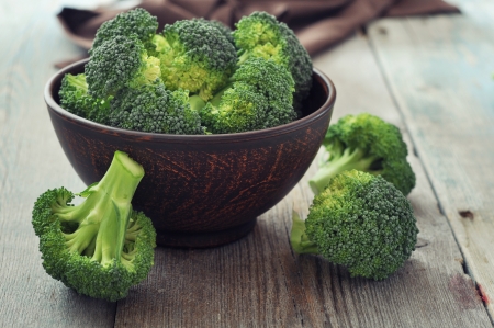 Bunch of fresh green broccoli in brown bowl over wooden backgroundの写真素材