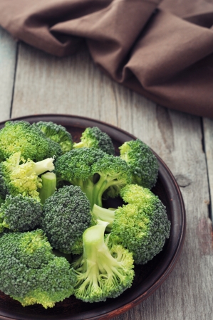 Bunch of fresh green broccoli on brown plate over wooden backgroundの写真素材